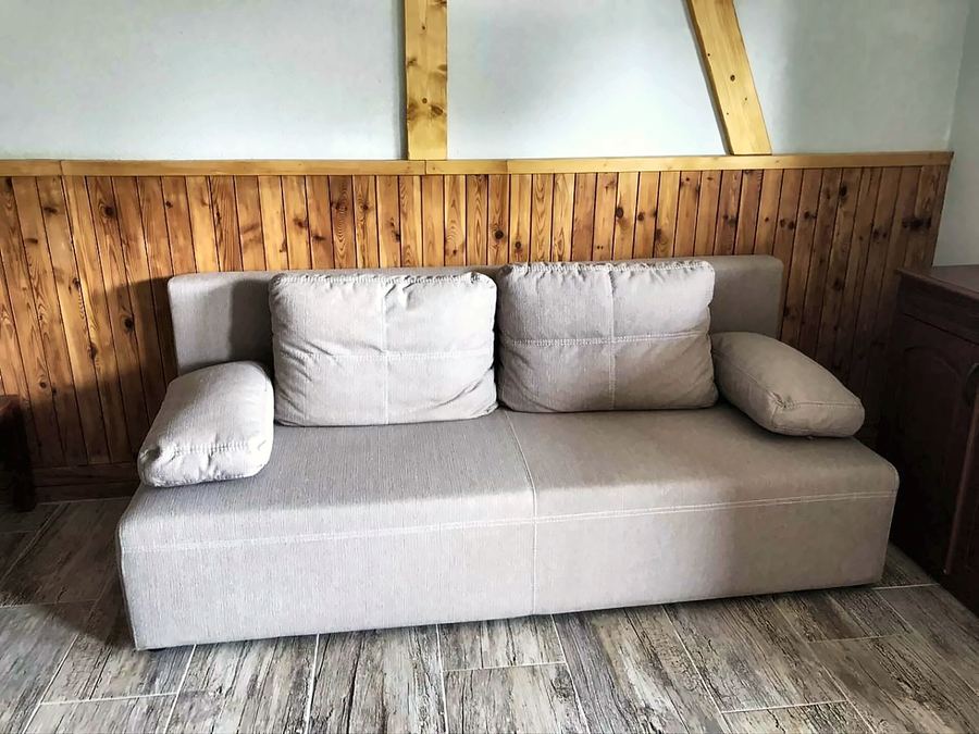 Světlá pohovka u dřevěného obložení stěny