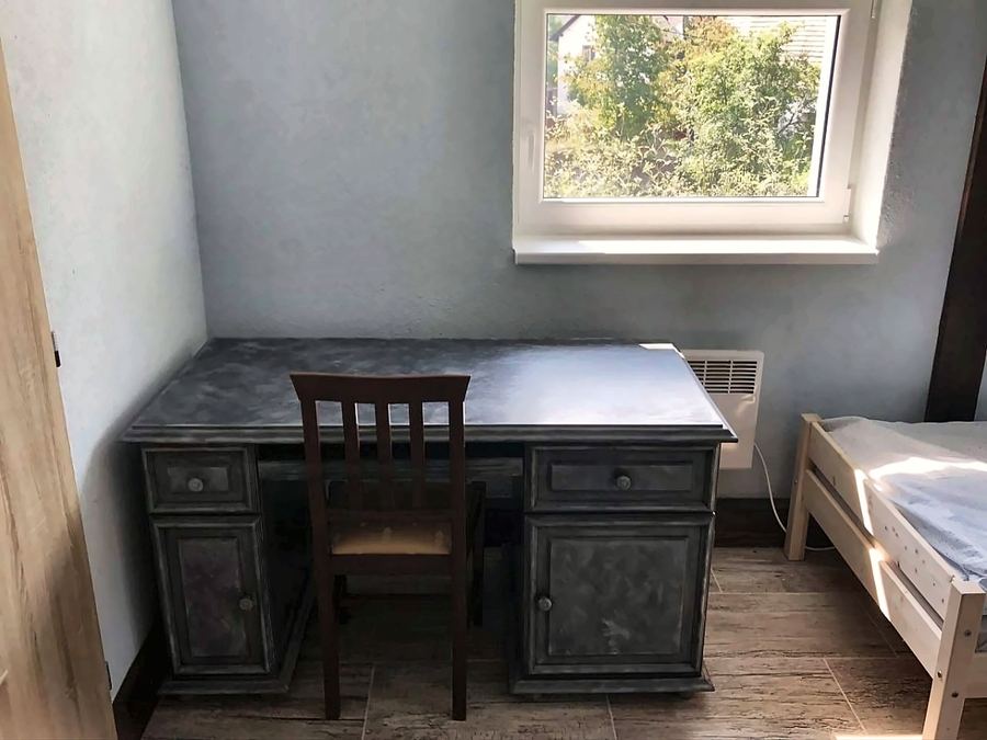 Masivní psací stůl se židlí pod oknem